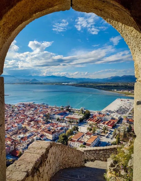 Ville et baie vues à travers une arche de pierre dans le Péloponnèse